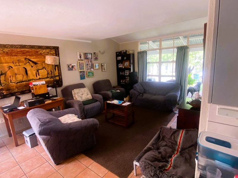 A comfortable living room featuring tiled flooring and a large glass sliding door providing natural light and access to the outdoor area.