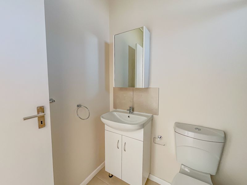 A clean and functional bathroom featuring a white vanity cabinet with basin, mirrored medicine cabinet, and a standard toilet.