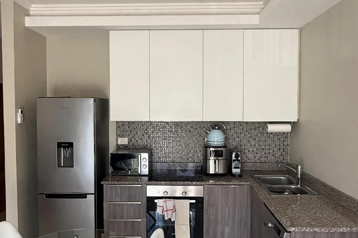 A functional kitchen featuring modern two-tone cabinetry, granite countertops, a mosaic tile backsplash, and integrated stainless steel appliances.
