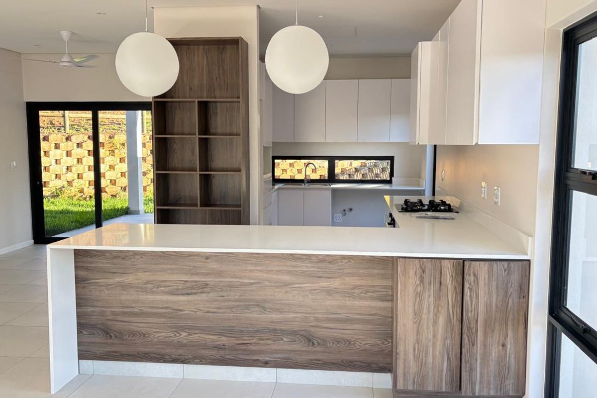 Modern kitchen featuring two-tone cabinetry, stone countertops, a gas hob, and built-in shelving, with direct access to the outdoor patio area.