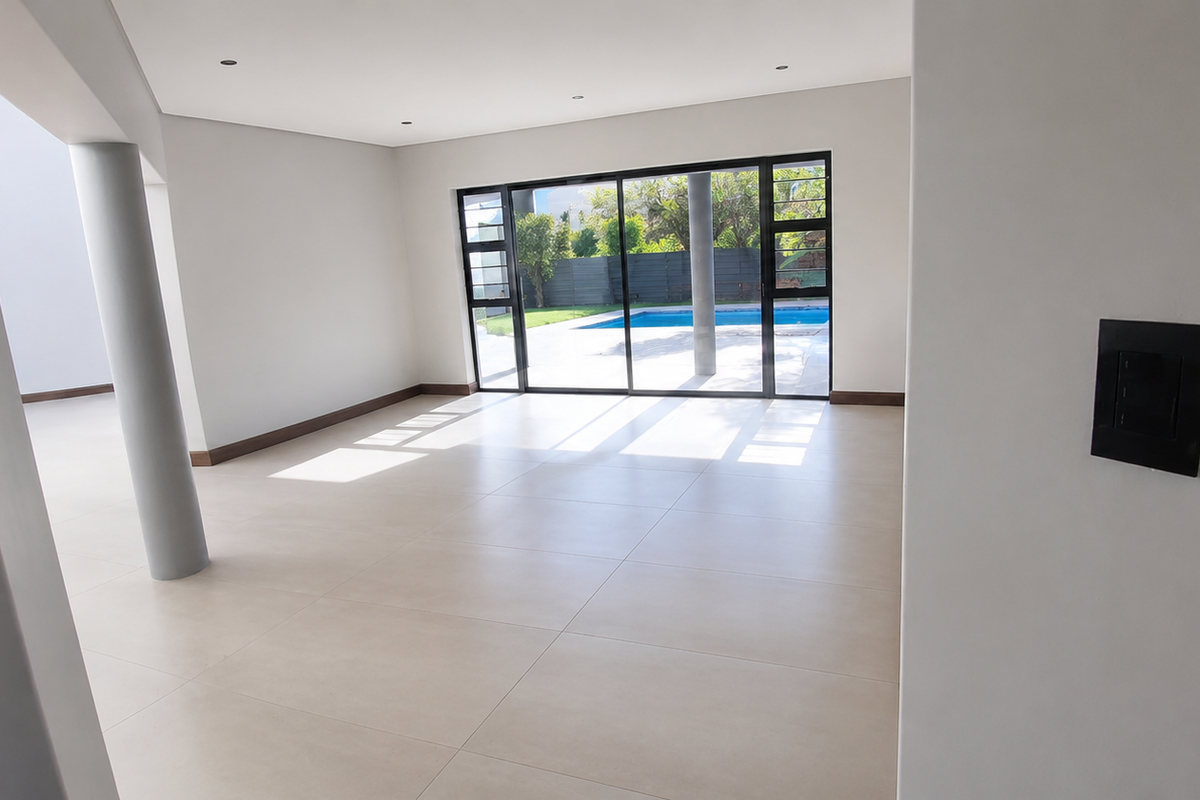 Spacious, light-filled living area featuring large format floor tiles, recessed lighting, and sliding glass doors opening to a private pool area.