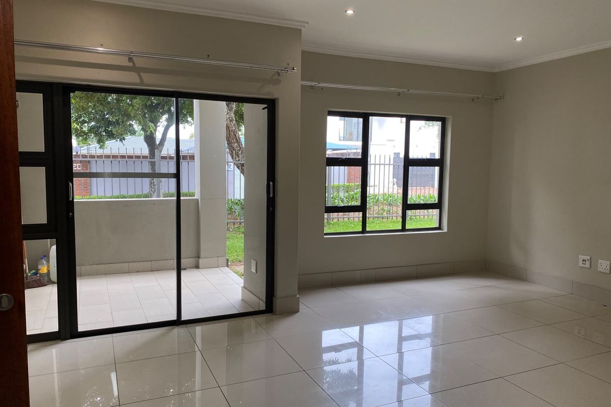 Bright and spacious living area featuring polished porcelain tiles, recessed lighting, and large sliding glass doors providing direct access to an outdoor patio.