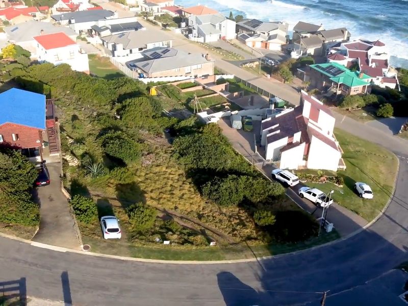Aerial view of a vacant residential plot situated in a coastal neighborhood, offering proximity to the ocean and established surrounding properties.