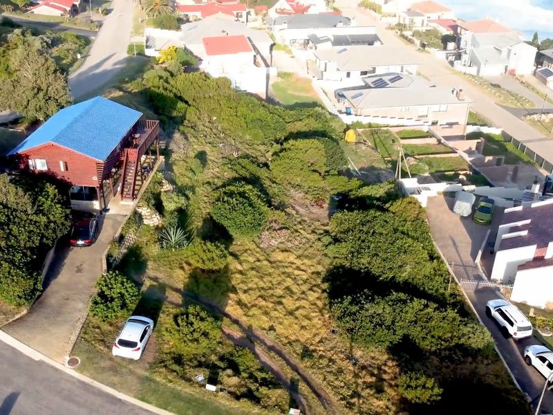Aerial view of a residential vacant land plot situated in a coastal neighborhood, featuring established vegetation and adjacent existing residential properties.