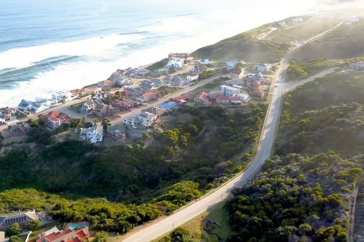 An aerial view of a coastal residential area showing the proximity of homes to the ocean and the surrounding natural landscape.