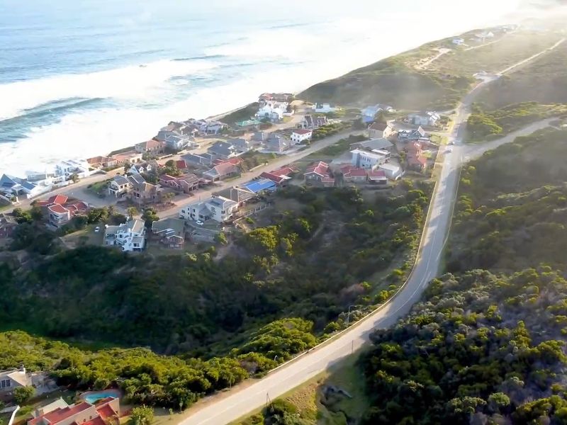 An aerial view of a coastal residential area showing the proximity of homes to the ocean and the surrounding natural landscape.