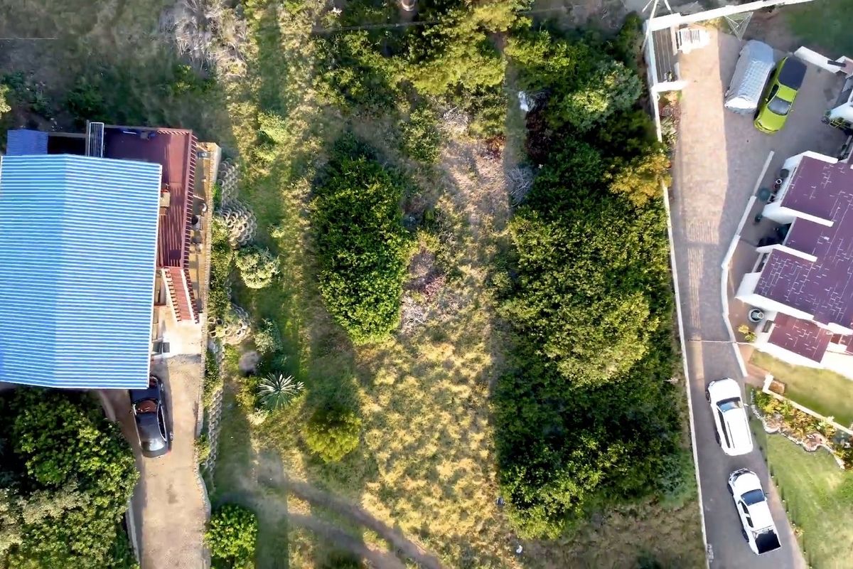 Aerial view of a residential property featuring a landscaped garden, paved driveway, and existing building structures.