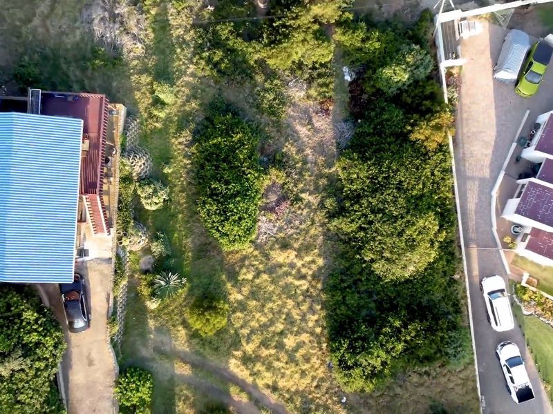 Aerial view of a residential property featuring a landscaped garden, paved driveway, and existing building structures.