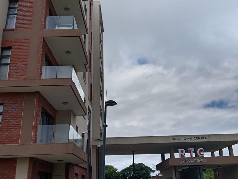 Exterior view of the Ridge Town Central apartment complex, featuring a modern brick facade, glass balconies, and a secure gated entrance.