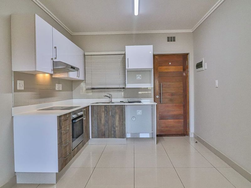 Modern kitchen featuring built-in cabinetry, electric hob, oven, extractor fan, and tiled flooring, providing a clean and functional space.