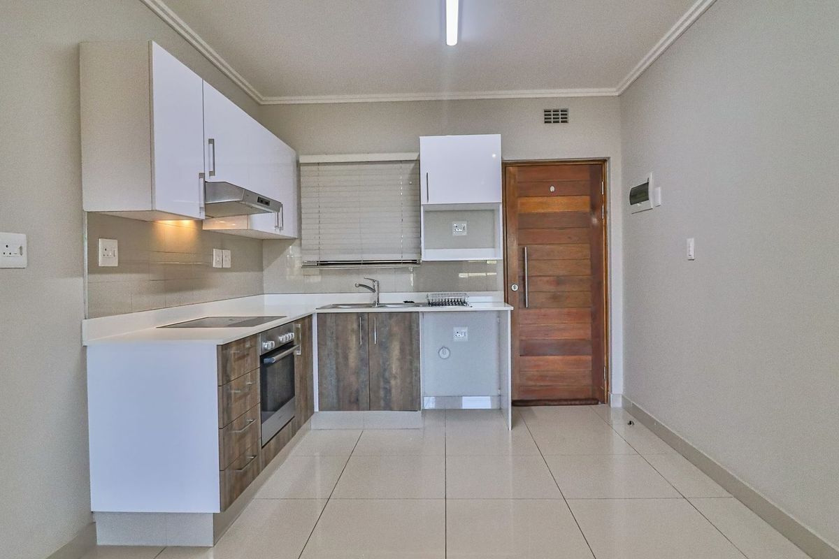 Modern kitchen featuring built-in cabinetry, electric hob, oven, extractor fan, and tiled flooring, providing a clean and functional space.