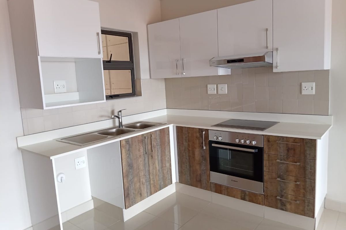 Modern kitchen featuring two-tone cabinetry, stone countertops, integrated electric hob, oven, extractor fan, and a double sink with tiled splashback.