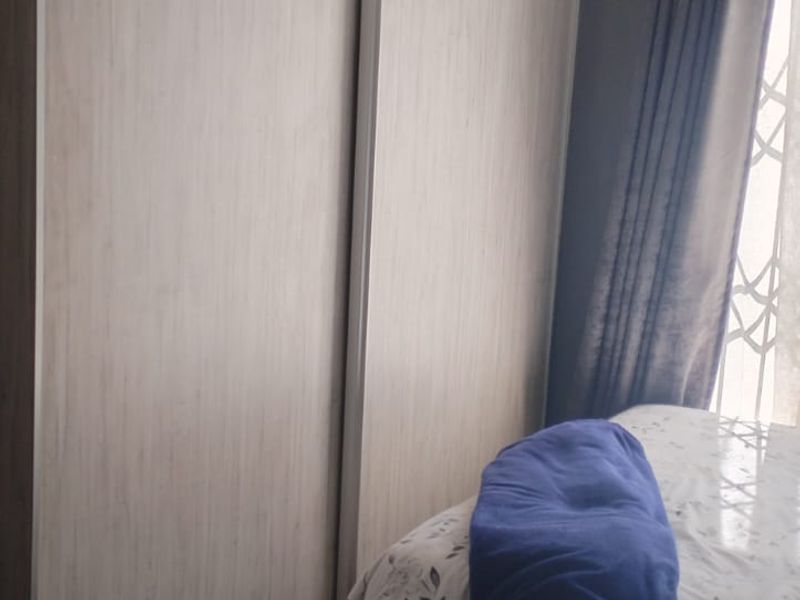 A bedroom featuring a modern light wood-finish built-in sliding door wardrobe and tiled flooring.