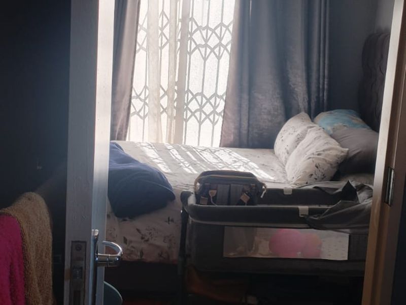 A bedroom featuring tiled flooring and a security gate on the window, viewed from the doorway.