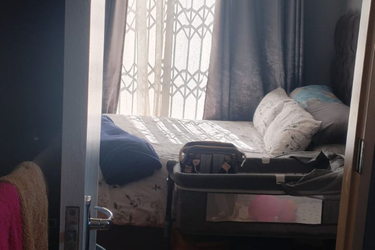 A bedroom featuring tiled flooring and a security gate on the window, viewed from the doorway.