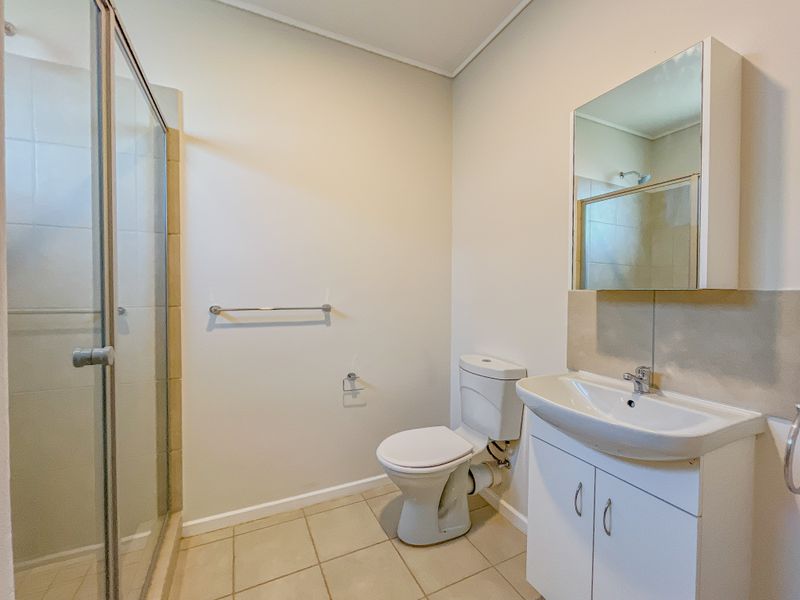 A functional bathroom featuring a shower enclosure, a white vanity with a basin, a mirror cabinet, and a standard toilet.