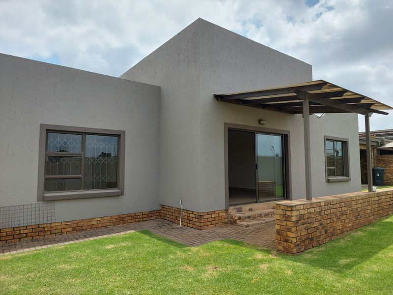 Rear view of the townhouse featuring a covered patio, sliding glass door access, and a well-maintained private garden area.