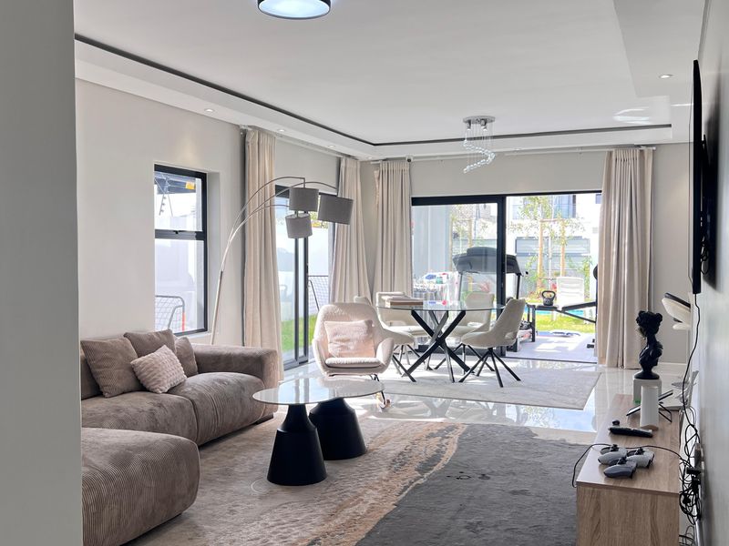 Spacious open-plan living and dining area featuring modern tiled floors, recessed ceiling lighting, and large sliding glass doors opening to the outdoor patio.