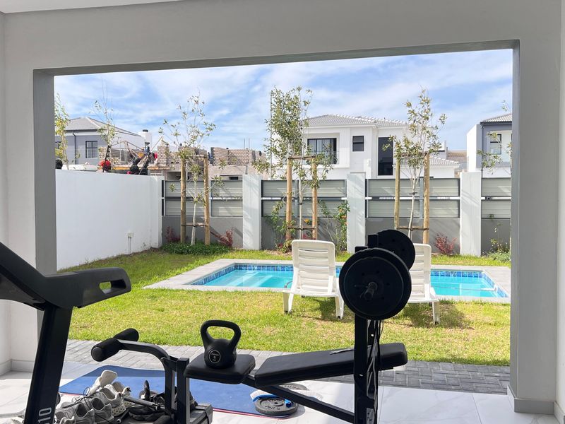Covered patio area overlooking a private garden with a swimming pool and secure boundary wall.
