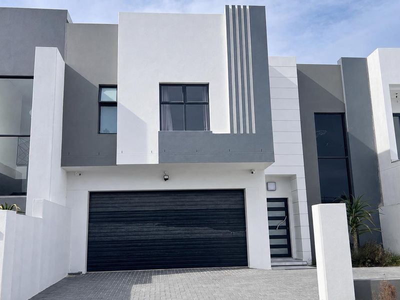 Modern double-story residential facade featuring a sleek contemporary design, paved driveway, and integrated double garage.