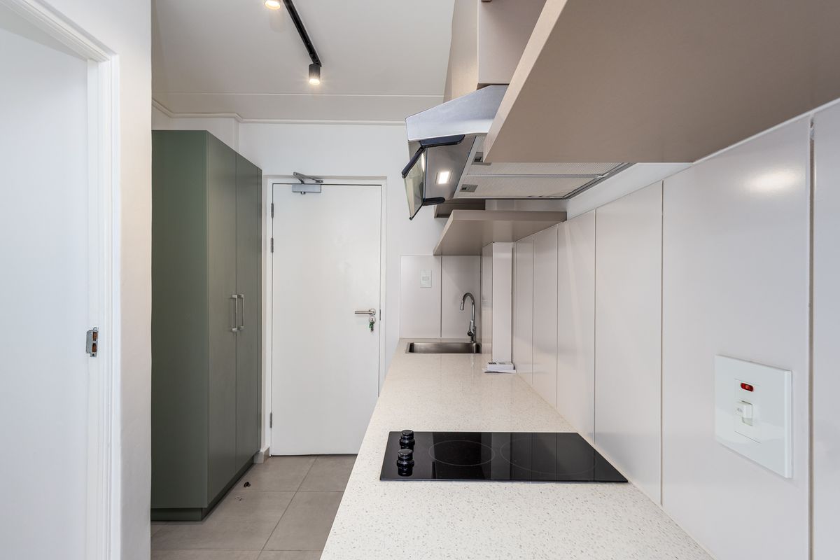 A clean, modern kitchen featuring built-in cabinetry, a stone countertop, an electric hob, and an integrated extractor fan.
