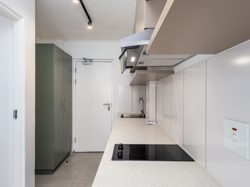 A clean, modern kitchen featuring built-in cabinetry, a stone countertop, an electric hob, and an integrated extractor fan.