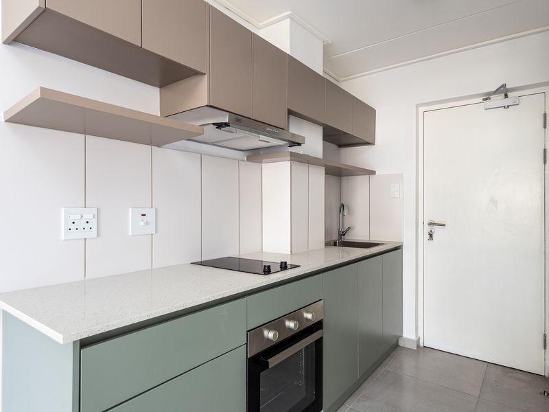 Modern kitchen featuring sleek sage green lower cabinetry, neutral upper cabinets, stone countertops, integrated electric hob, oven, and extractor fan.