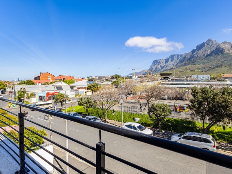 Elevated view from a balcony overlooking the surrounding neighborhood, street, and mountain landscape.