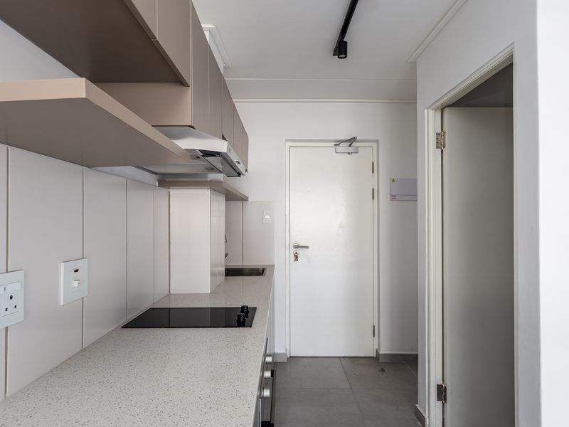 Modern kitchen featuring sleek built-in cabinetry, stone countertops, an integrated electric hob, and an extractor fan, finished with clean tiled flooring.