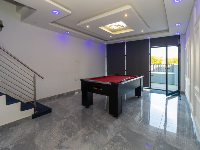 Modern living area featuring polished tiled floors, a recessed ceiling with integrated LED lighting, and direct access to an outdoor patio area.