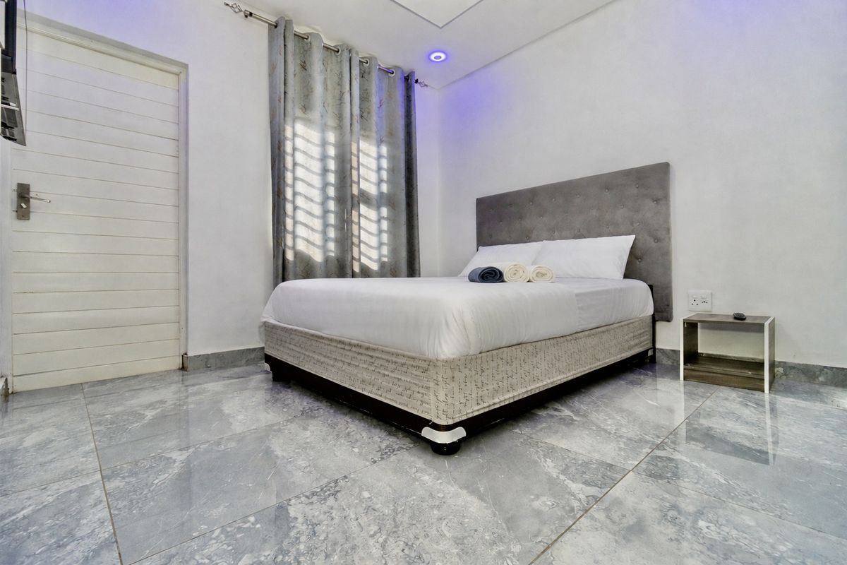 A well-maintained bedroom featuring polished grey tiled flooring, recessed ceiling lighting, and a neutral interior finish.