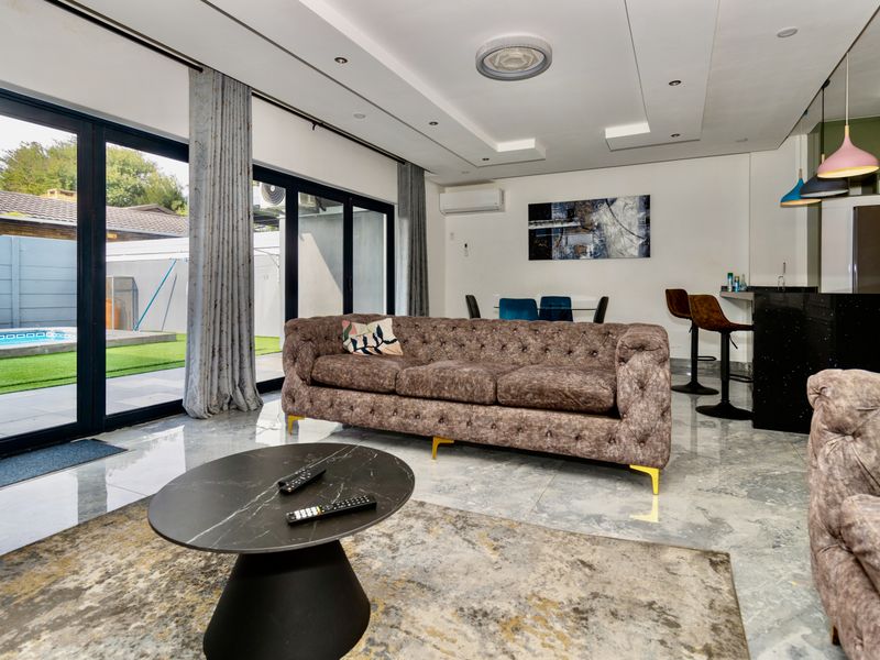Modern open-plan living area featuring sleek tiled floors, recessed lighting, and large sliding glass doors that provide seamless access to the outdoor pool area.