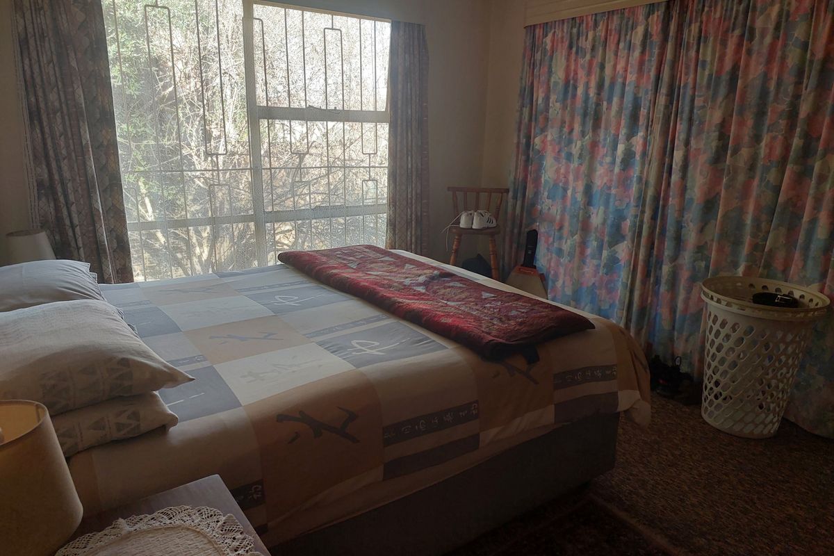 A bedroom featuring carpeted flooring, large windows with security bars, and curtain rails, offering a functional space ready for modern updates.