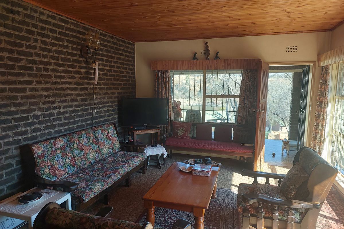 A living room featuring an exposed brick wall, timber ceiling, and direct access to an outdoor patio area.