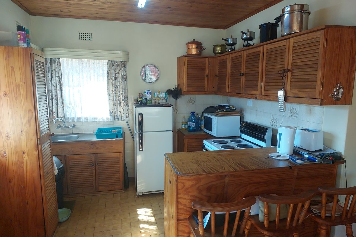 A functional kitchen featuring timber cabinetry, a breakfast bar, and a tiled backsplash, offering potential for a modern renovation.