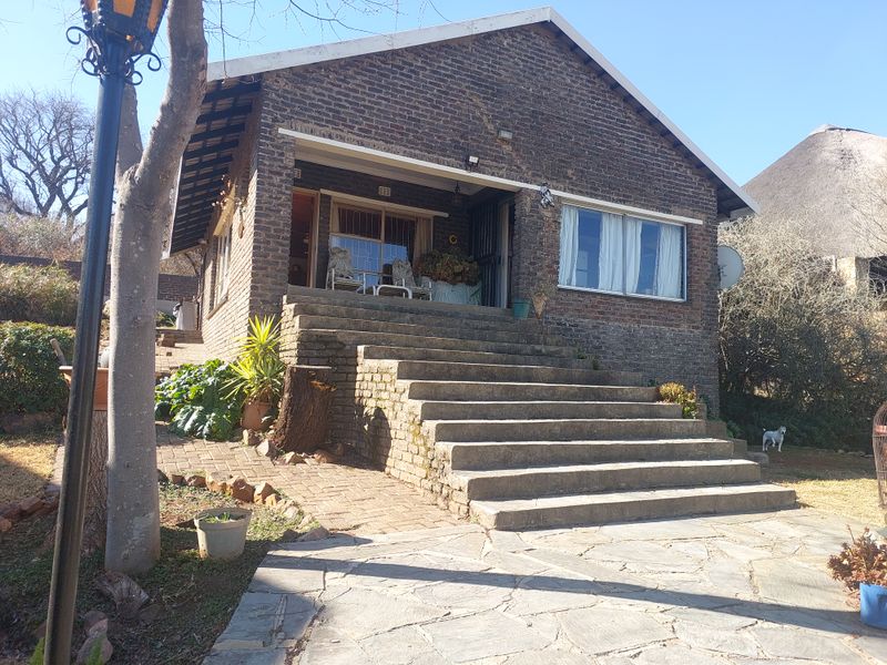 Front view of a brick-faced house featuring a prominent concrete staircase leading to a covered entrance and patio area.