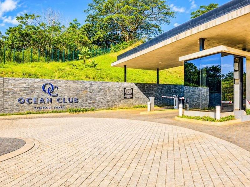 The entrance to the Ocean Club at Zimbali Lakes, featuring a modern security gatehouse, stone-clad feature wall, and paved driveway.