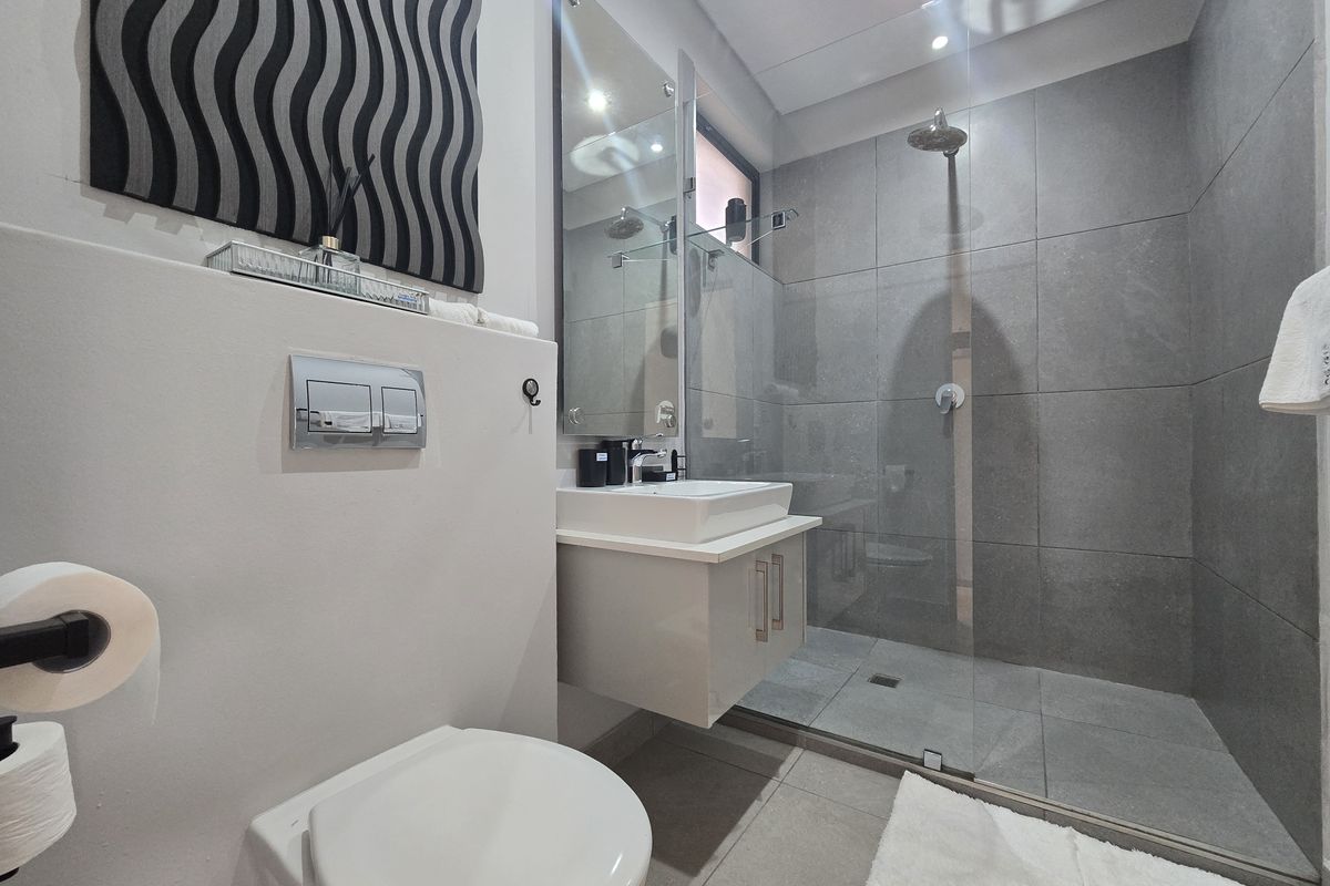 Modern bathroom featuring a wall-hung toilet with concealed cistern, floating vanity with vessel sink, and a spacious walk-in shower with glass screen.