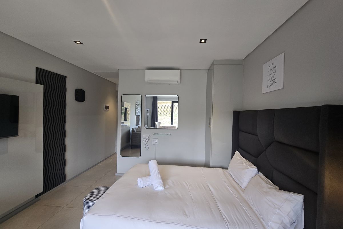 Modern bedroom featuring tiled flooring, recessed downlighting, a split-system air conditioner, and built-in wardrobe storage.