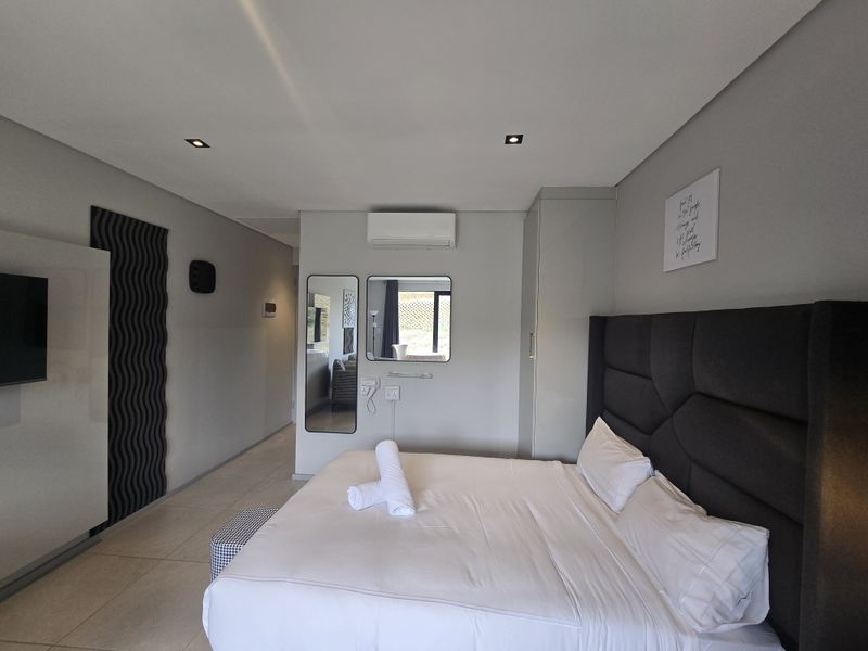 Modern bedroom featuring tiled flooring, recessed downlighting, a split-system air conditioner, and built-in wardrobe storage.