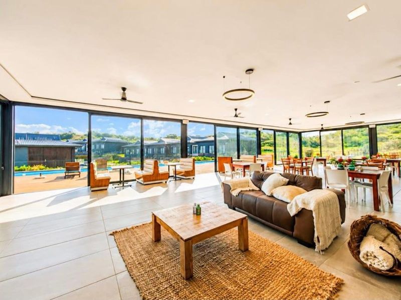 Spacious open-plan living and dining area featuring expansive floor-to-ceiling sliding glass doors that provide seamless access to the outdoor pool deck.