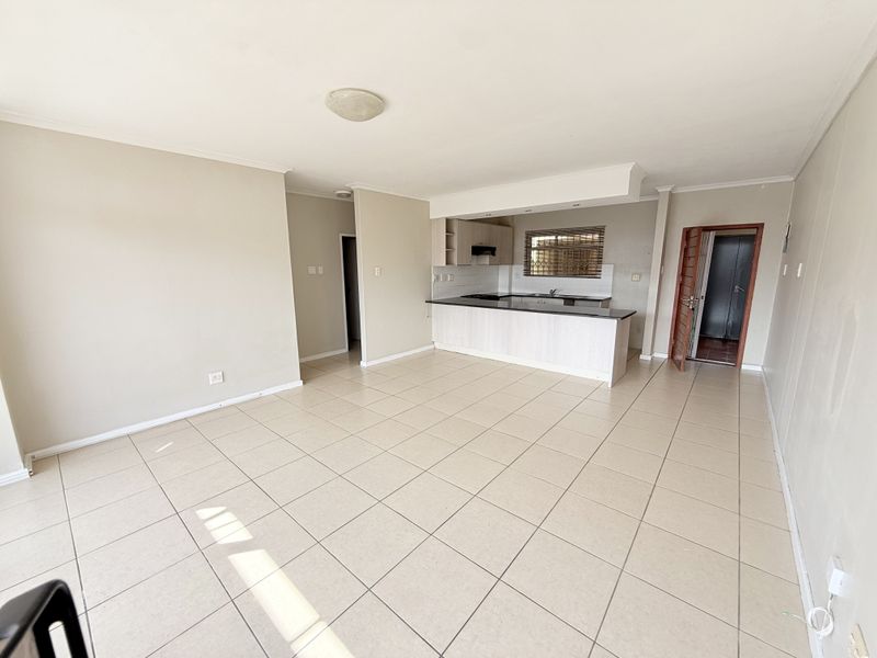 Spacious open-plan living area featuring tiled flooring and a functional kitchen with built-in cabinetry, granite countertops, and integrated cooking appliances.