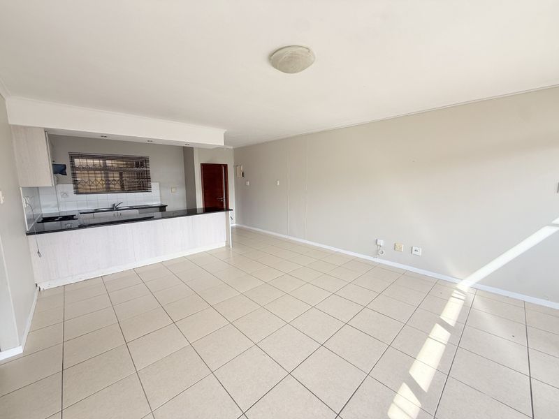 Spacious open-plan living area featuring tiled flooring and a functional kitchen with granite countertops and built-in cabinetry.
