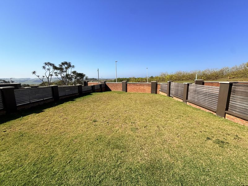 A well-maintained private garden area featuring brick boundary walls with integrated timber slat fencing and open lawn space.