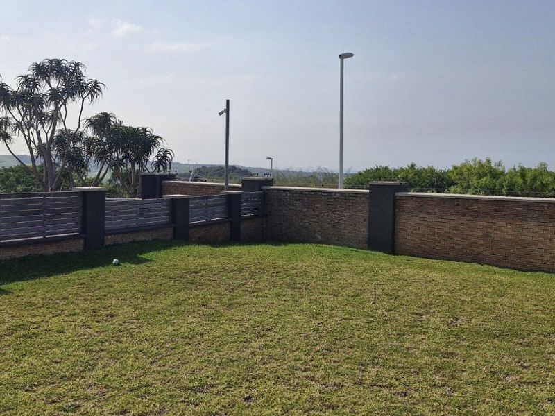 A well-maintained private garden area featuring a combination of brick and timber boundary fencing, manicured lawn, and integrated exterior lighting.