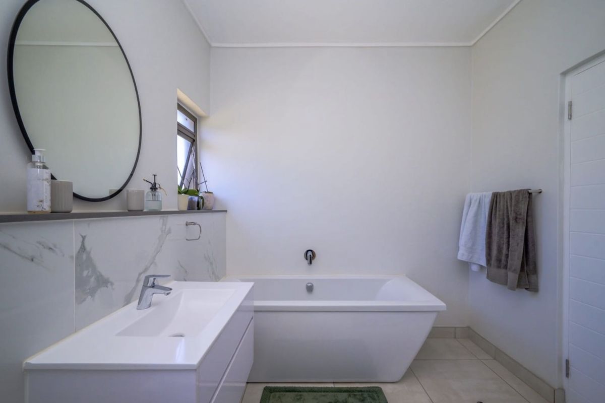 Modern bathroom featuring a sleek freestanding bathtub, a contemporary vanity with a basin, and elegant marble-look wall tiling.
