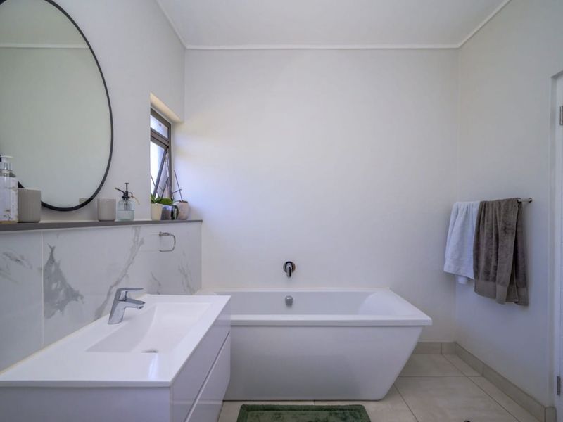 Modern bathroom featuring a sleek freestanding bathtub, a contemporary vanity with a basin, and elegant marble-look wall tiling.