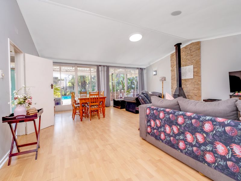 Spacious open-plan living and dining area featuring laminate flooring, a stone-clad fireplace, and large sliding doors providing natural light and garden access.