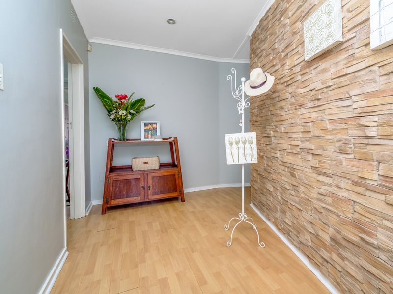 A bright hallway featuring light laminate flooring and a textured stacked stone feature wall, creating a warm and welcoming entrance.