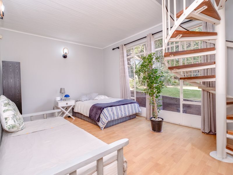Spacious bedroom featuring laminate flooring, a unique spiral staircase, and large glass sliding doors providing natural light and garden views.